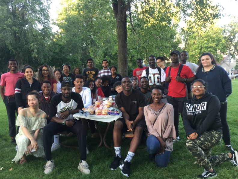 Club members pose around a picnic table at a park.