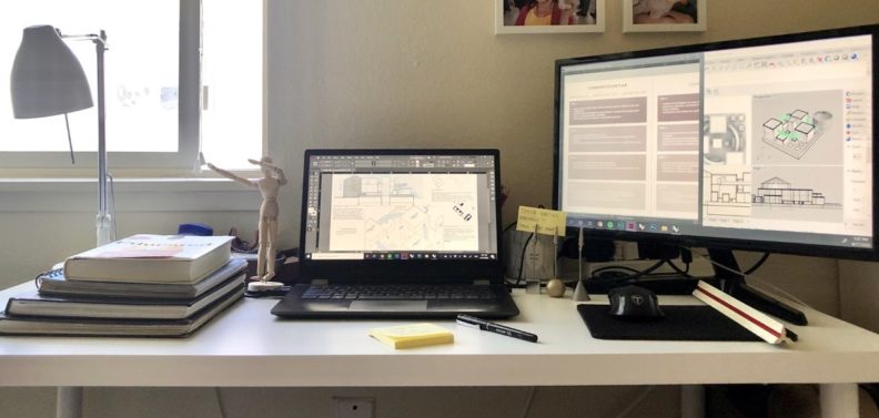 A laptop, monitor, and books on a desk.