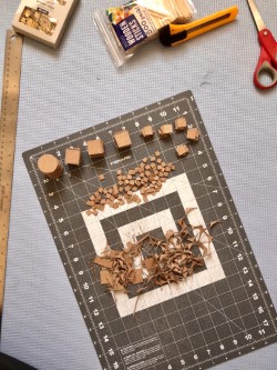 Wooden model-making pieces on a cutting mat with scissors and a utility knife.