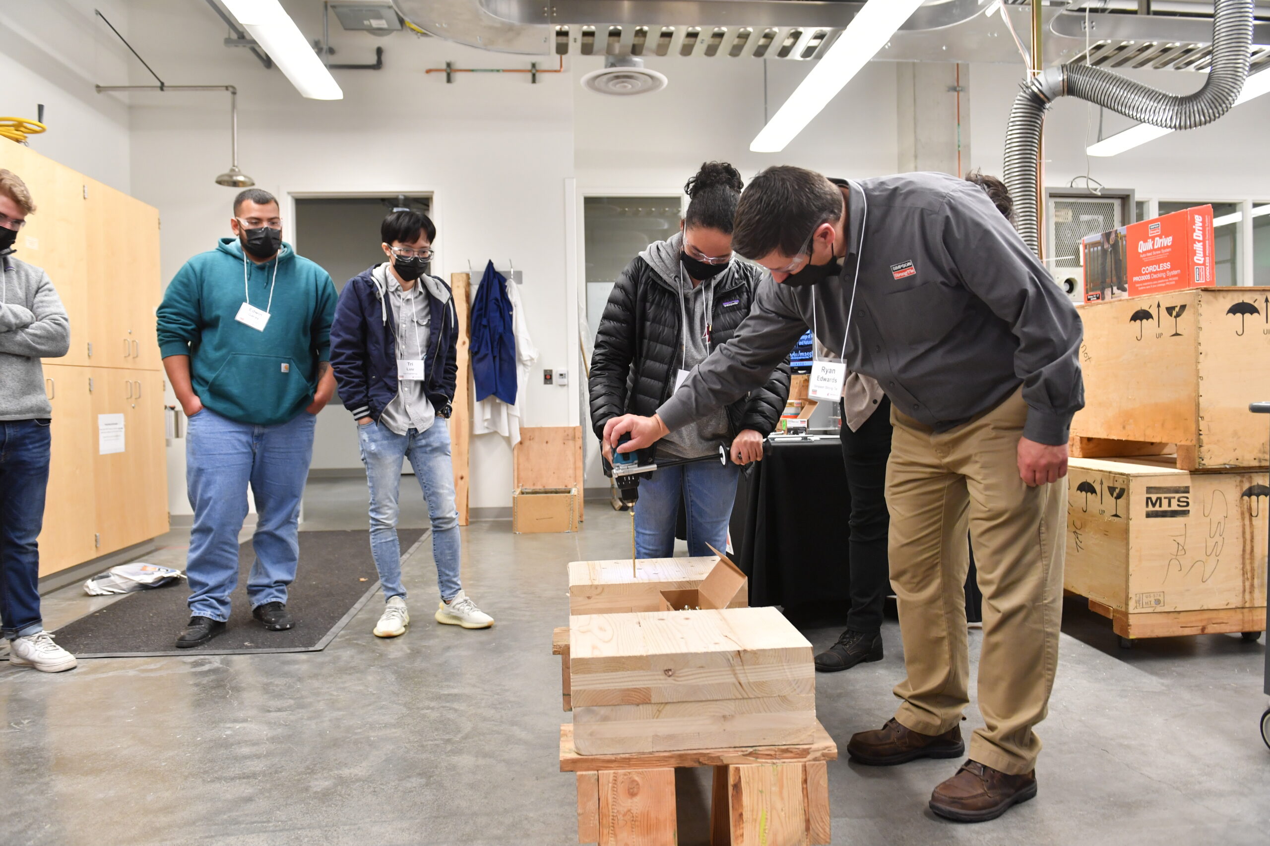Student and presenter demonstrate using a drill and wood fastener.