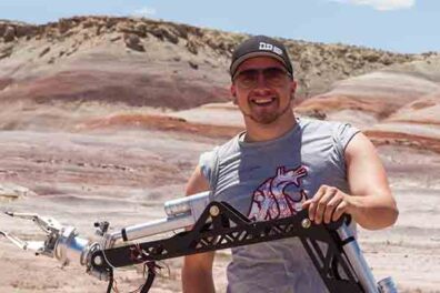 Blaine Liukko poses with a robotic rover arm.