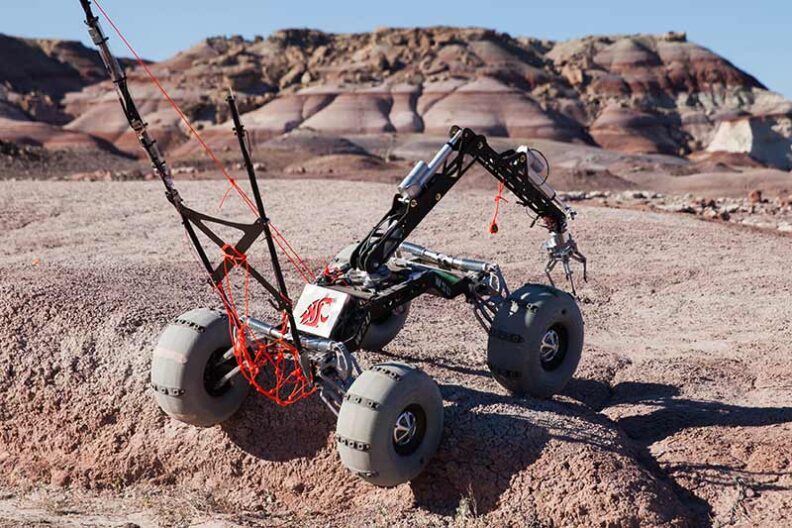 Robotic rover climbing over a terrain obstacle.