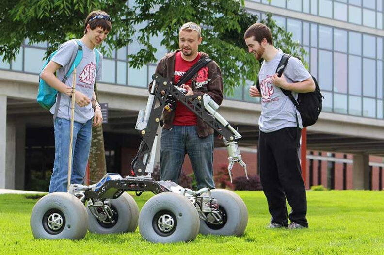 Three men talking next to a robotic rover on the WSU Everett campus.