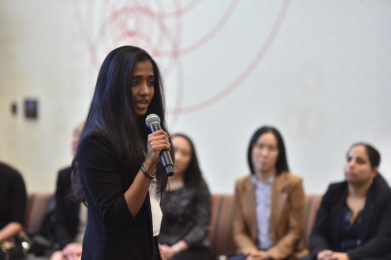 Woman holding a microphone presenting to a group.