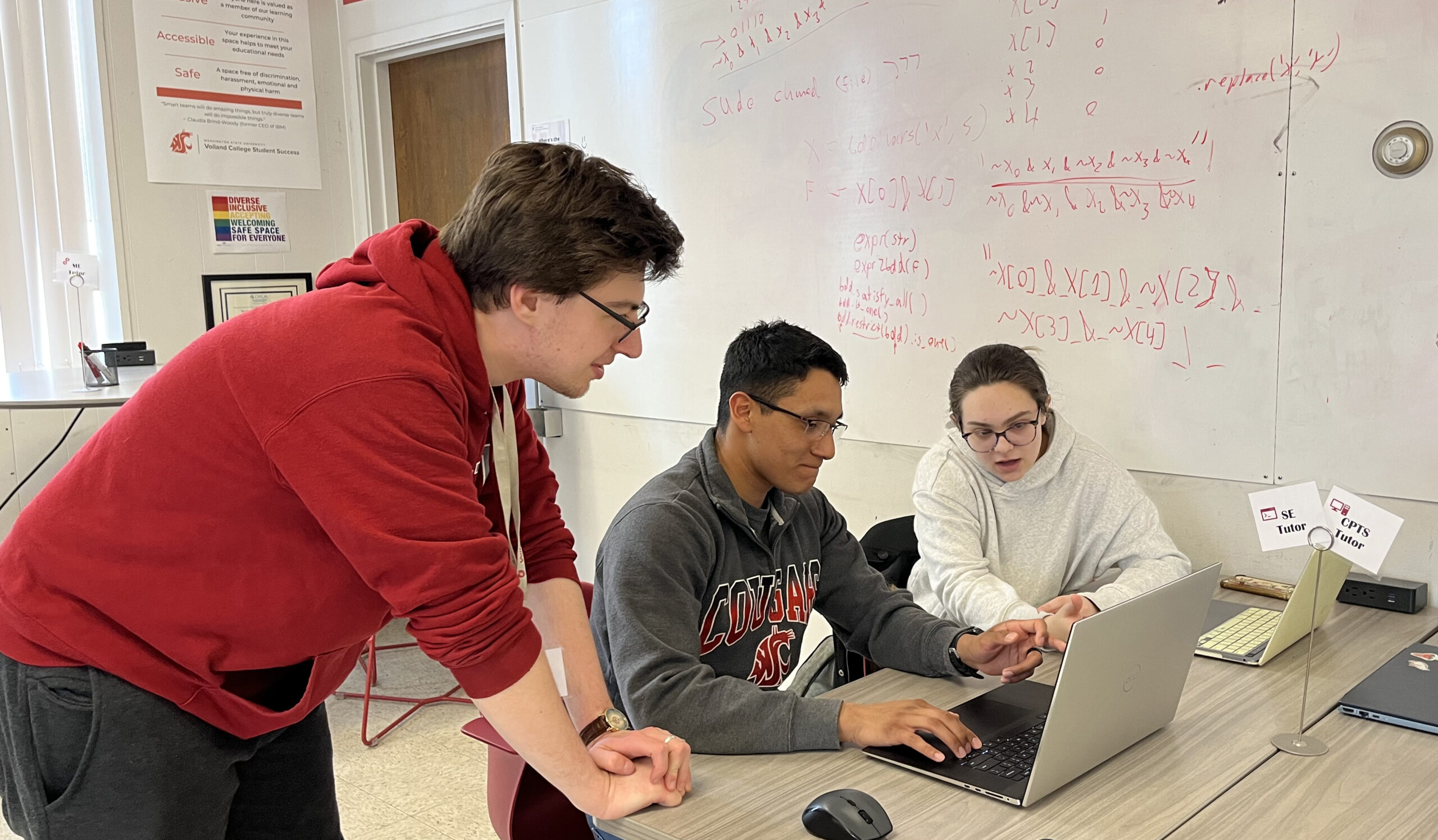 Three students looking at a laptop in a tutoring center.