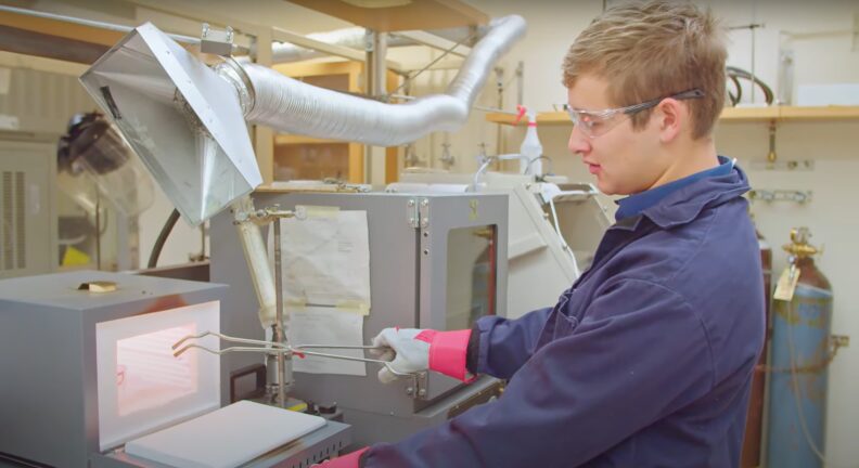 Man wearing protective gear and holding tongs.