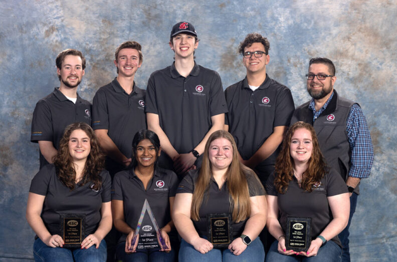 Eight students and their advisor pose with their awards.
