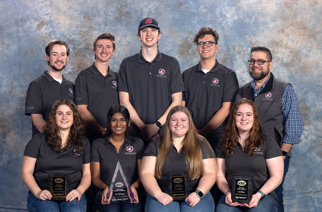 Eight students and their advisor pose with their awards.