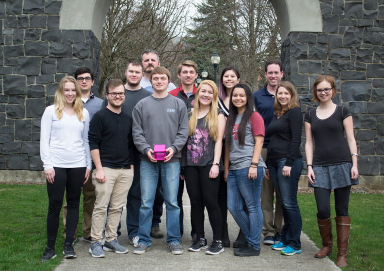 Students pose while displaying a cube.