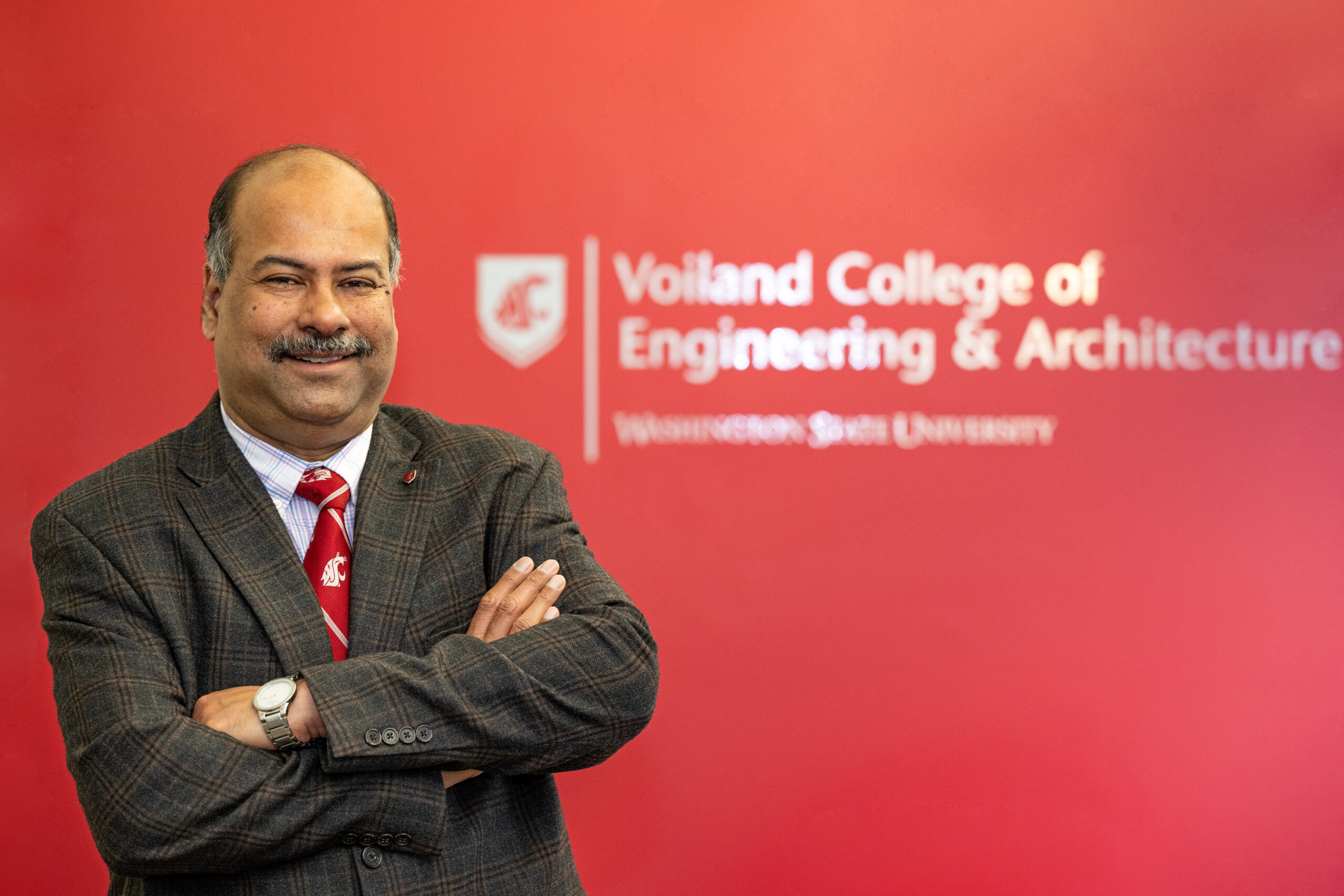 Partha Panda in front of a wall that has the Voiland College logo.