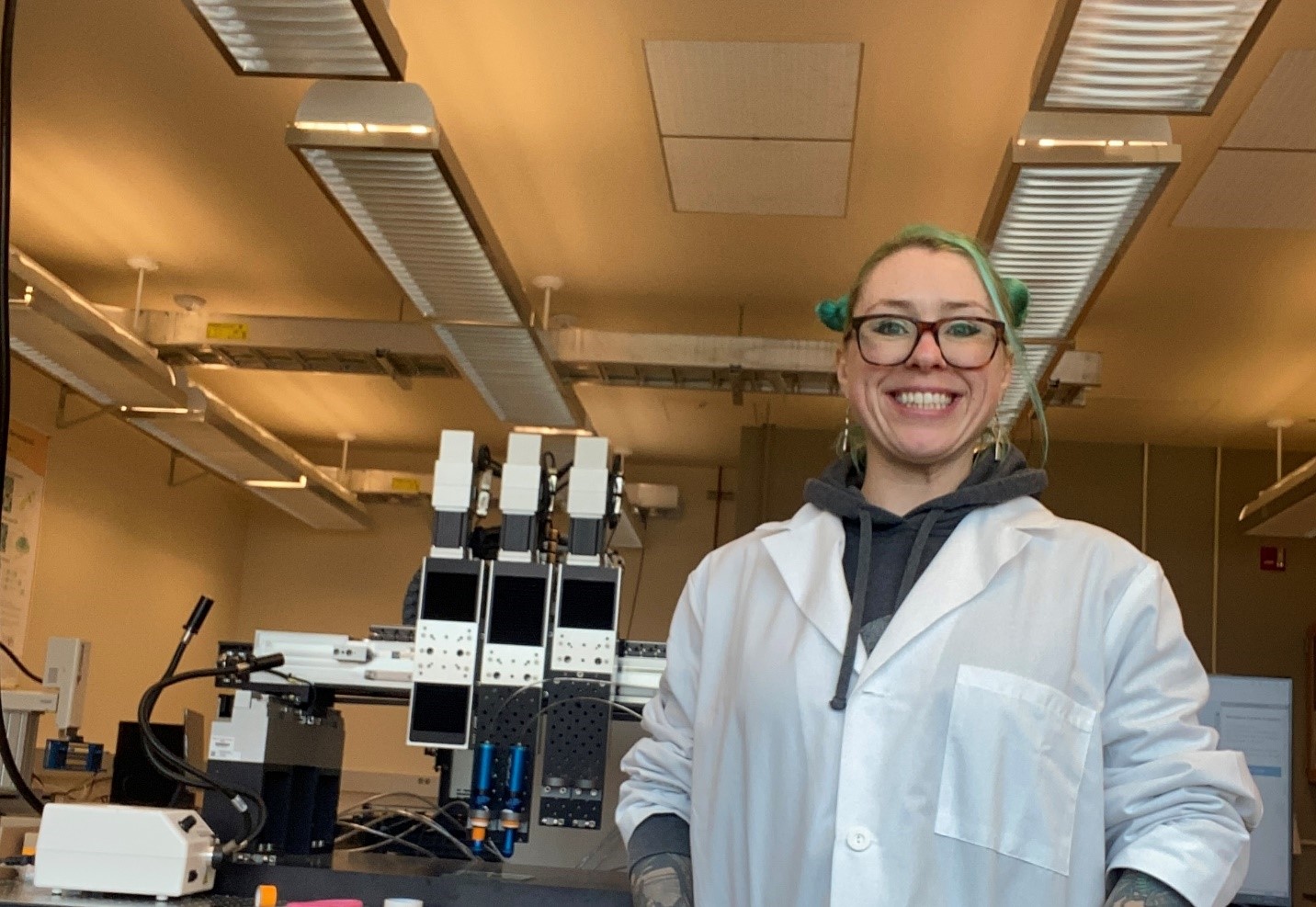 Sonja Sparks wearing a lab coat and standing next to equipment.