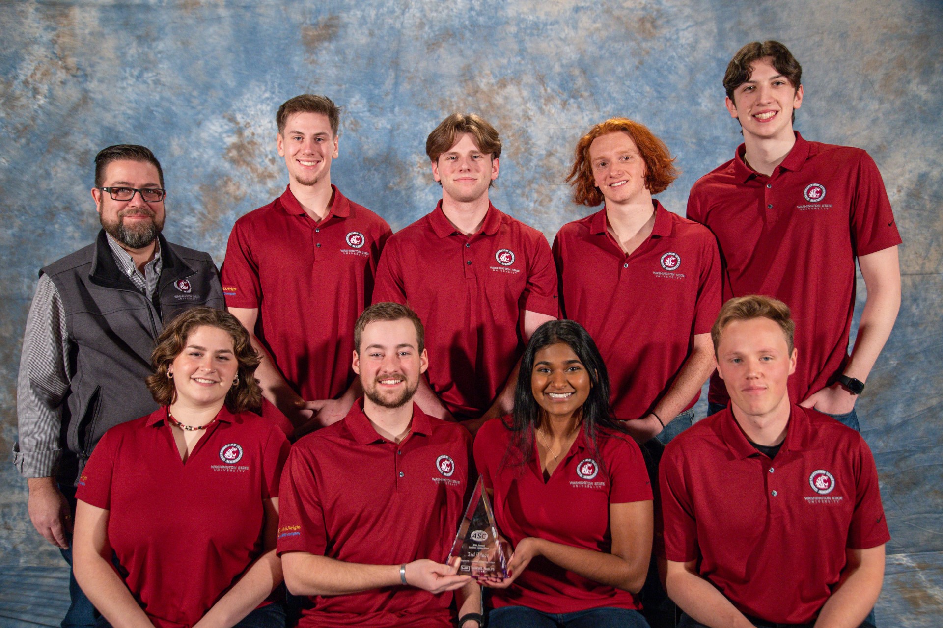 Nine people posing with their competition award.