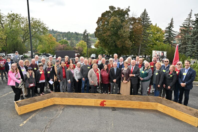 Group photo of donors, faculty, staff, and other attendees behind a planter bearing the Washington State University Cougar logo during the Schweitzer Engineering Hall groundbreaking ceremony.
