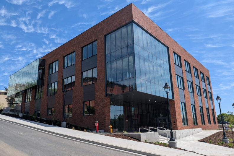 Exterior corner of a multi-story brick and glass building.