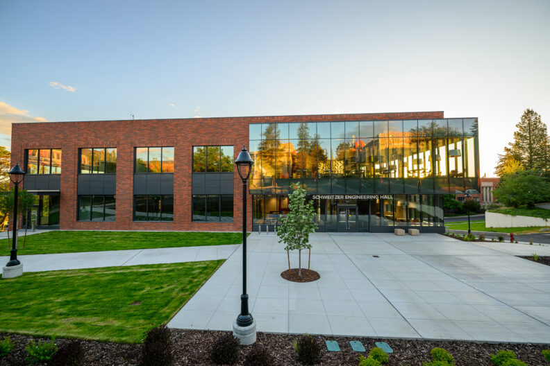 Exterior of a glass and brick building with a courtyard in front.