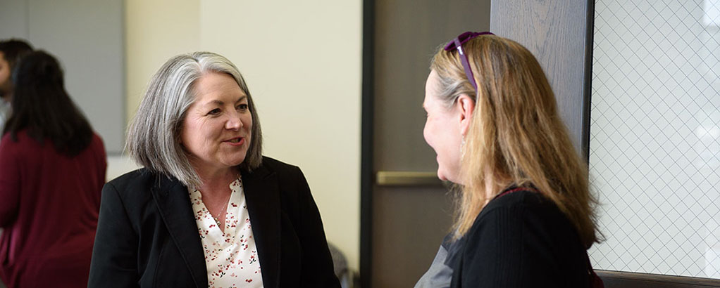 Kay Bachman talking to an ETM graduate during the graduation celebration.