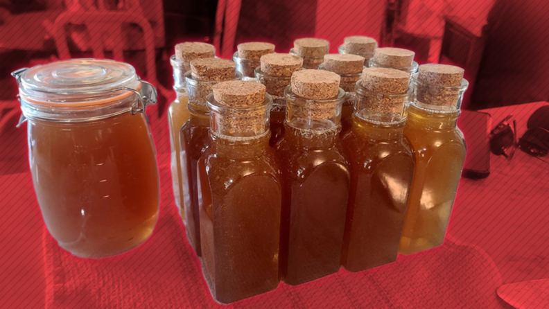 Several bottles of fresh honey sitting on a table. 