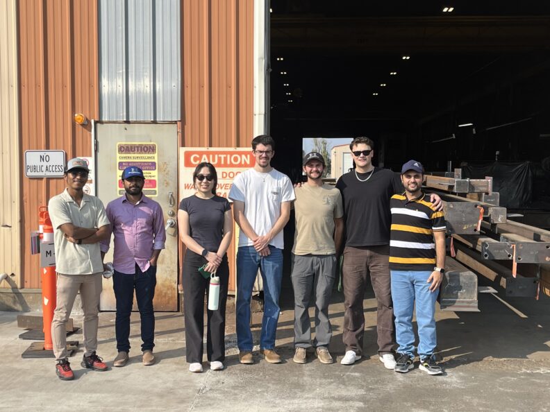 Seven students post outside a Metals Fabrication Company building.