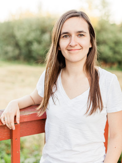 Woman leaning against a deck railing.