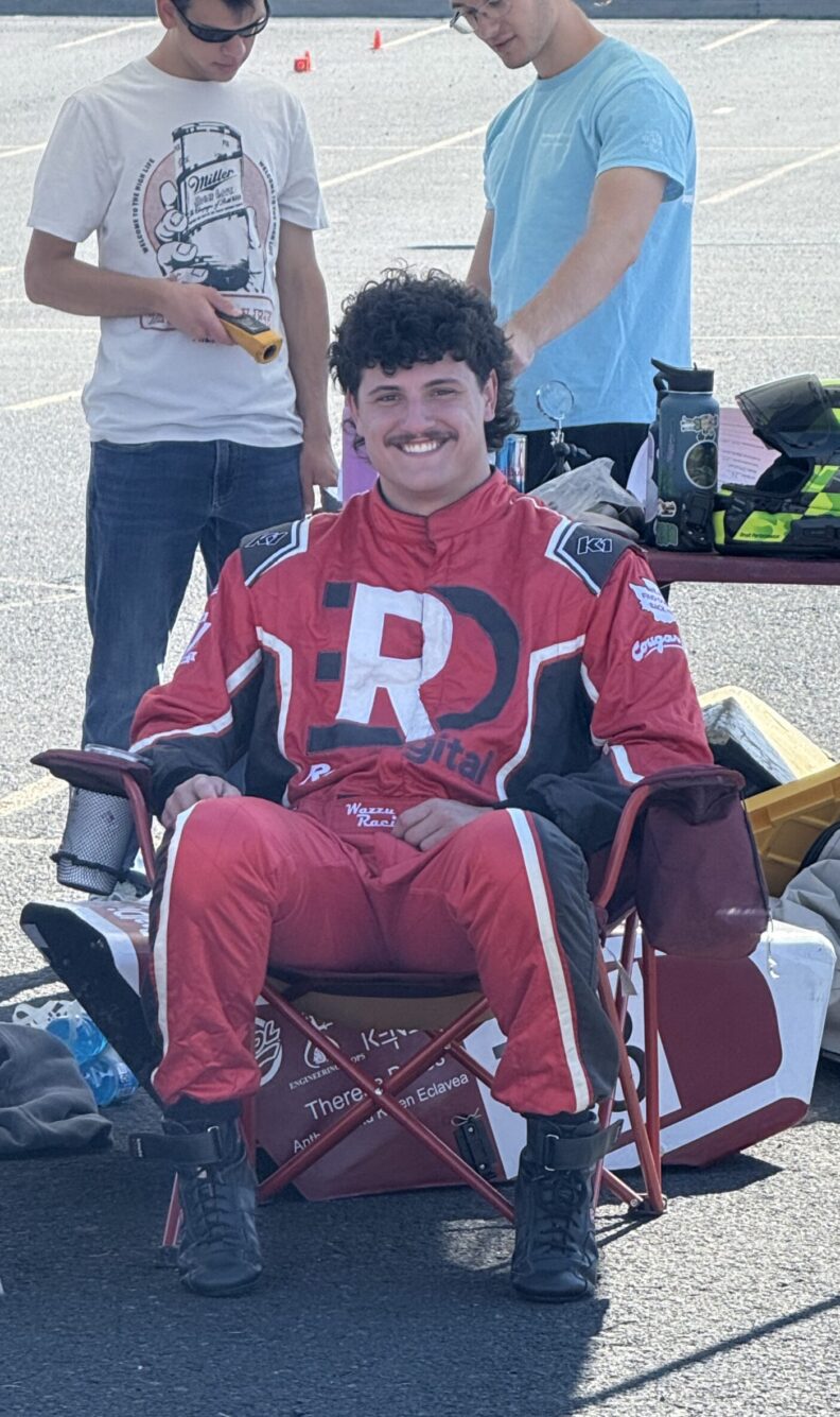 Man in a red racing suit sitting in a camping chair.