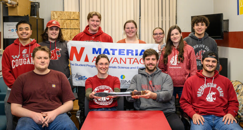 Group of students in coug gear holding a sword and a banner.