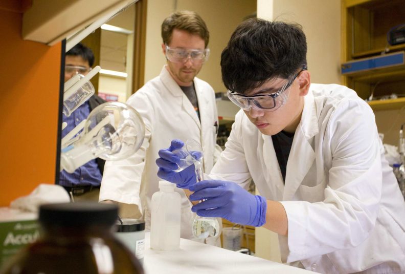 Researchers wearing PPE while mixing chemicals in a lab.