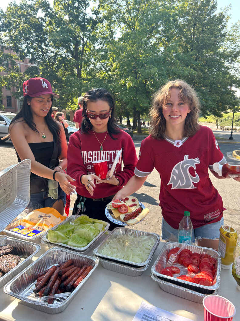 Three students showing off a plate of food filled from the buffet table in front of them.