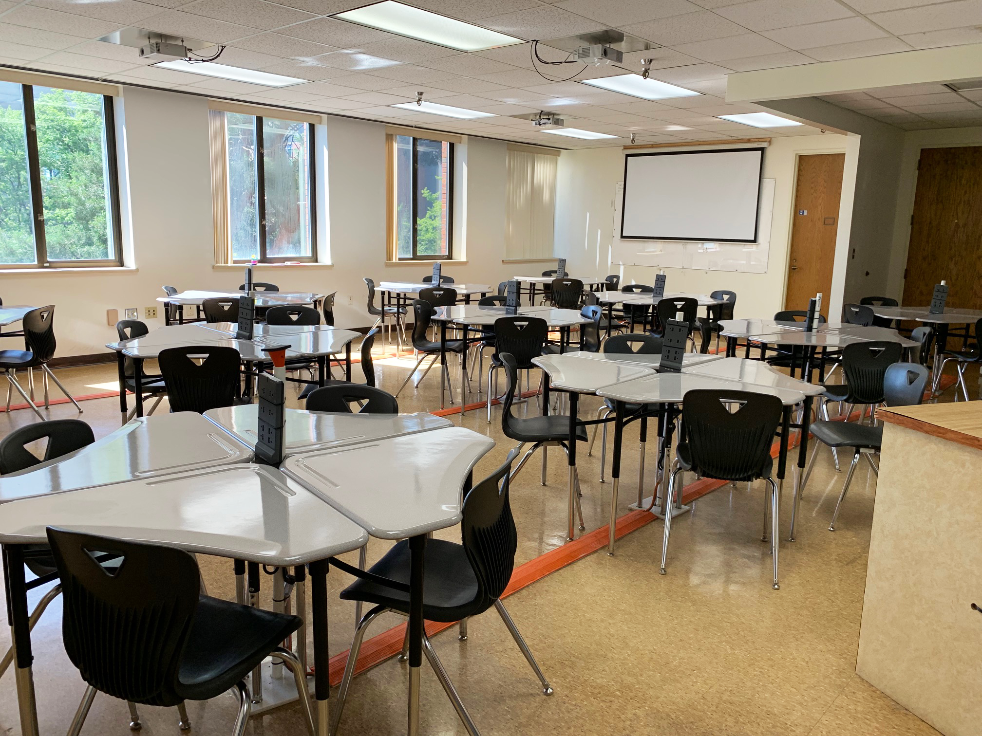 The image shows meeting tables and chairs with a projector at the end of the Bio-engineering Instruction Room in Wegner 205.