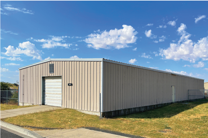 large, beige manufactured storage structure with a garage bay and a side door.
