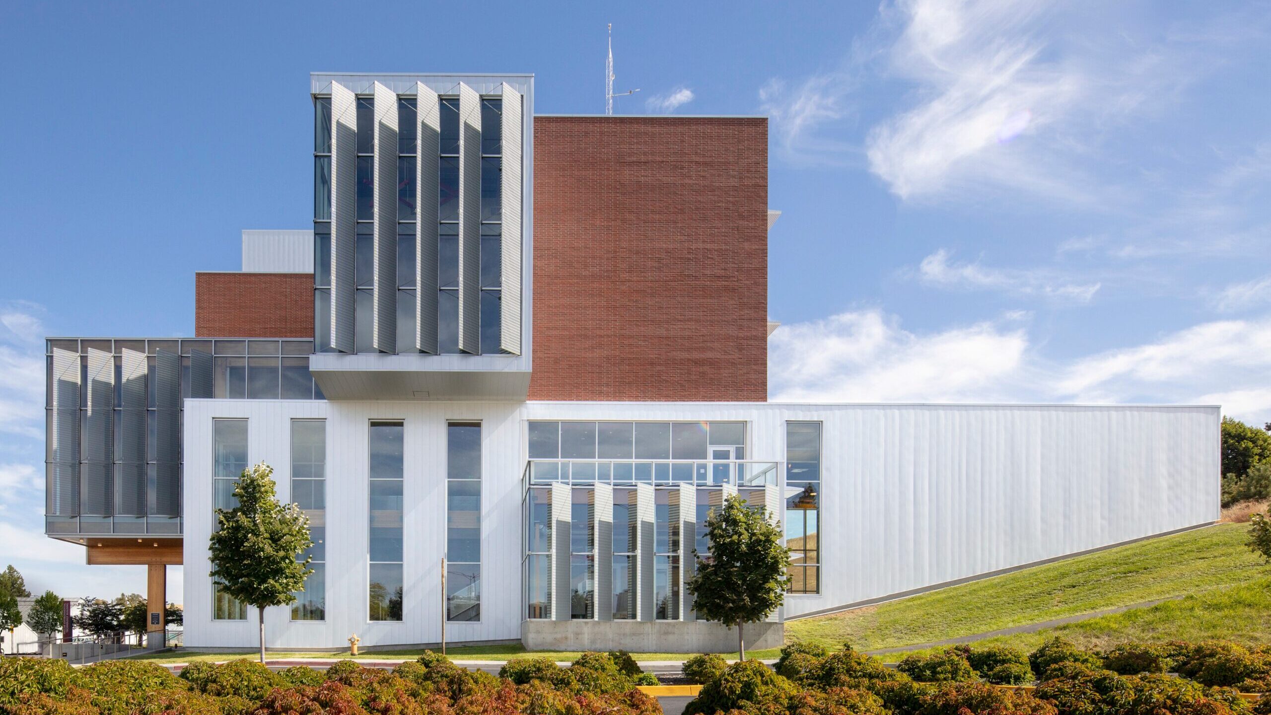 modern, multistory glass and brick building set into a small. hillside.