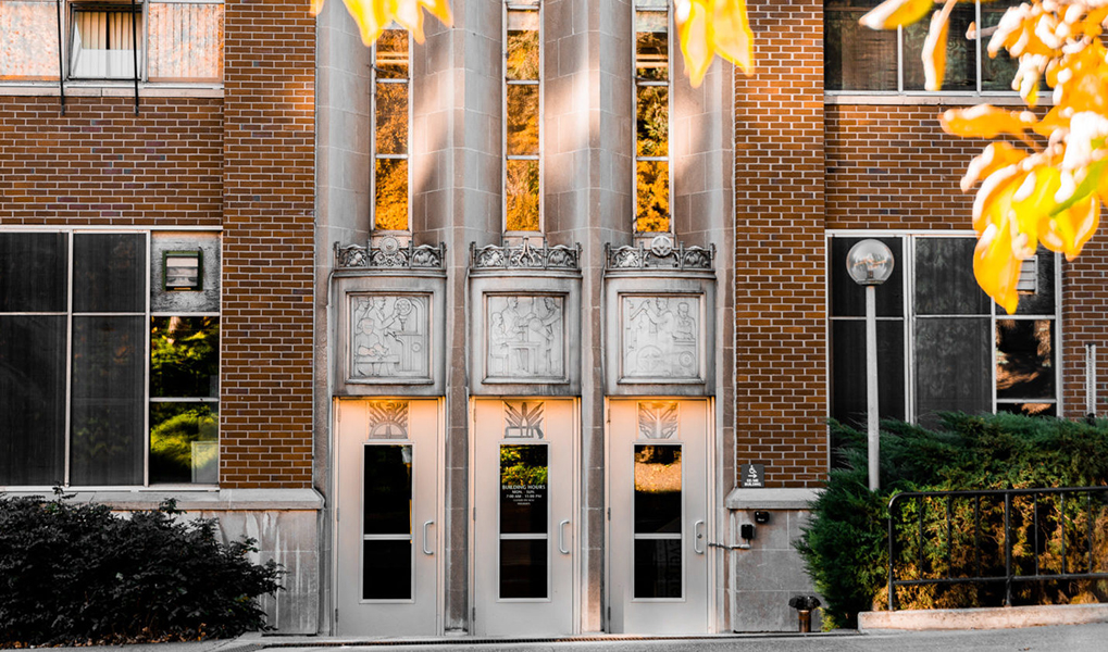 Entrance of a building with decorations showing artistic scenes above each door.