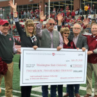 A large, ceremonial check is presented to WSU during a Cougar football game.