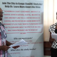 Eric Osoro and Hariet Mireiri in front of an informational sign on Zika