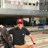 Pierce sitting on the steps next to a statue outside the clinic