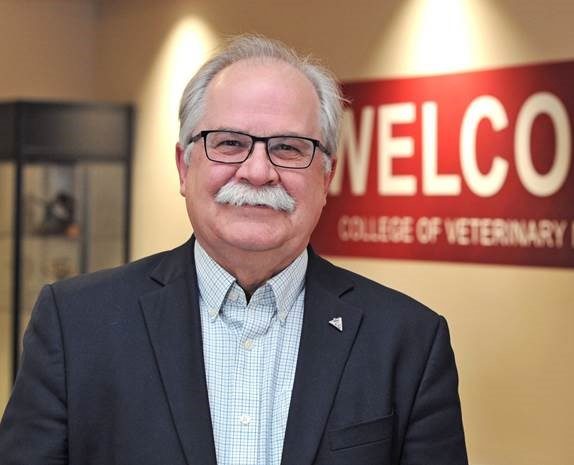 Dr. Slinker standing in front of a sign that says Welcome College of Veterinary Medicine