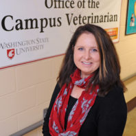 Standing in front of the Office of the Campus Veteriarian sign.