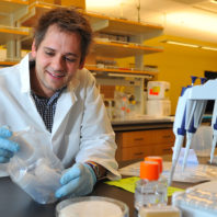 Letko sitting in the lab looking at lab supplies.