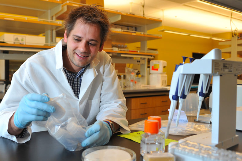 Letko sitting in the lab looking at lab supplies.
