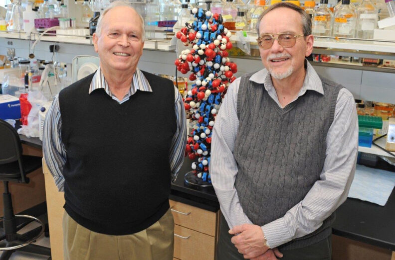 Raymond Reeves and Michael Smerdon standing in a laboratory with a DNA model behind them.
