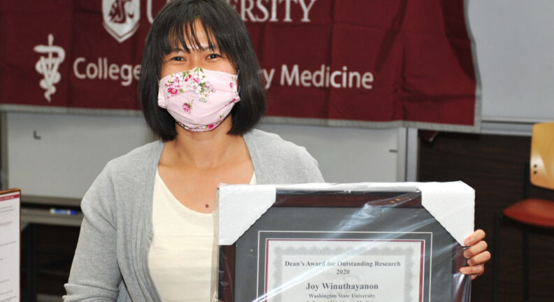 Dr. Joy Winuthayanon holding her framed certificate.