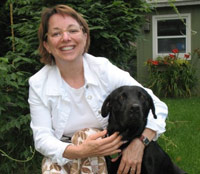 Lauren crouched down next to her black lab, and holding onto it.