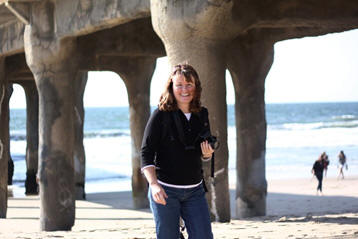 Debby on the beach with a pier behind her.