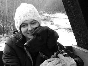 Black and white photo of Holly with her black lab. It is in the winter.