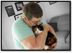 Photo of adult woman holding and kissing her cat.