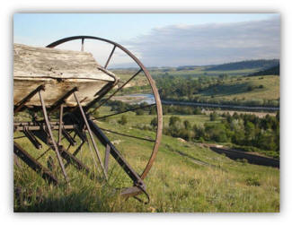 Farm machinery in the foreground. Valley with a river flowing through it in the distance.