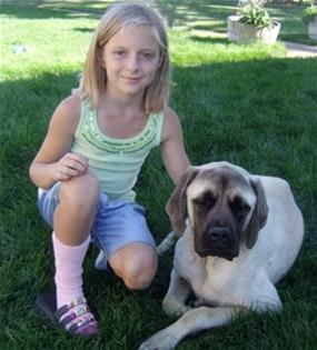 8-year-old Jenna and her mastiff, Timmy, sitting on the grass together.