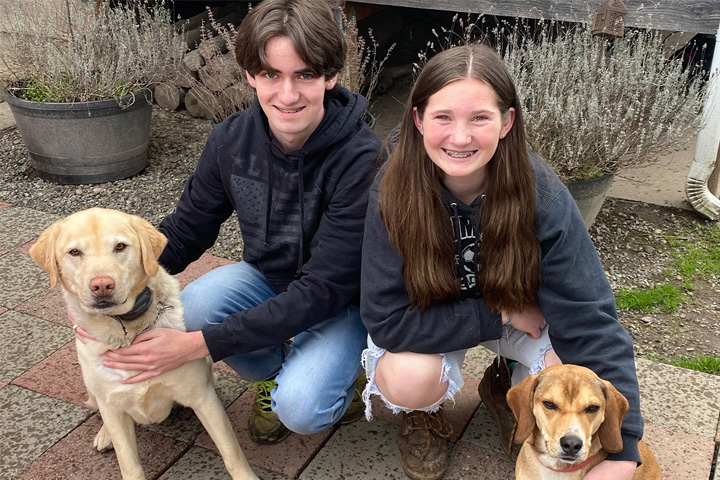 Carlitos, a young Beagle mix (right), sits with his family, (left to right) Remington, Royle Brazier and Mia Brazier.