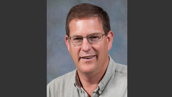 Professional headshot in a photo studio with a simple grey background.