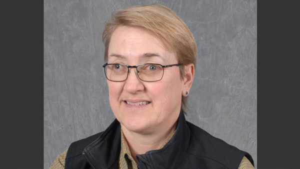 Professional headshot in a photo studio with a simple grey background.