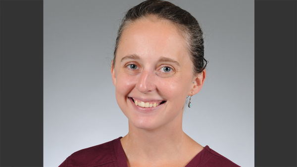 Professional headshot in a photo studio with a simple grey background.